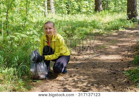Woman Runner Puts Litter In A Garbage Bag During Plogging In The Park