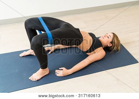 High Angle View Of Attractive Caucasian Woman Exercising Setu Bandha Sarvangasana With Resistance Ba