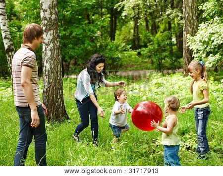 Família feliz ao ar livre com bola de plaing crianças na grama verde.