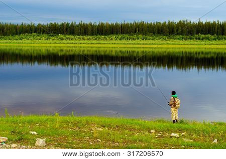 Yakut Girl Tourist Angler With A Backpack Pulls Out A Spinning Bait With The Grass From North Of The