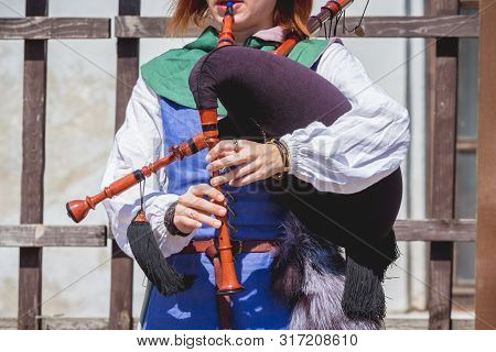 Woman In Medieval Clothes Playing On A Bagpipe