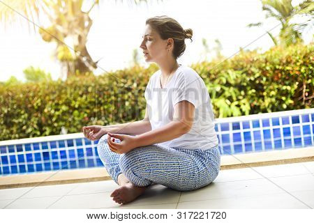 Woman Meditating At Pool Side With Clothed Eyes. Tropical Bsckground