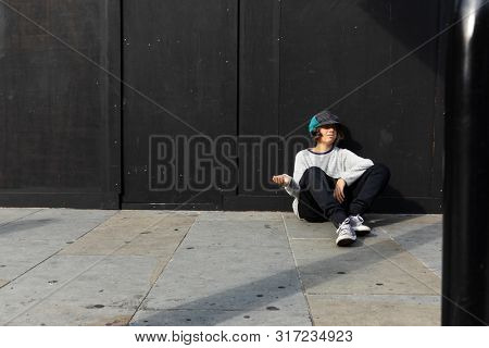 Portrait of boy with colorful hat asking for alms. Black background.