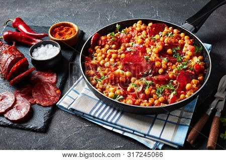 Close-up Of Garbanzos Fritos, Fried Chickpeas With Chorizo, Ham Tomatoes And Spices In A Skillet On 
