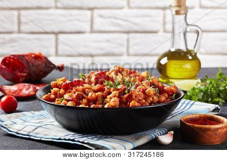 Close-up Of Garbanzos Fritos, Hot Chickpea Stew With Chorizo, Tomatoes And Spices In A Black Bowl On