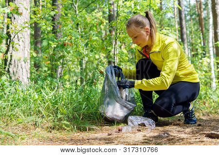 Woman Runner Puts Litter In A Garbage Bag During Plogging In The Park