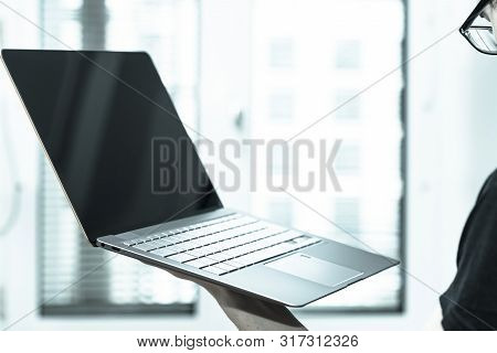 Young Freelancer Is Holding Up A Thin Elegant Notebook