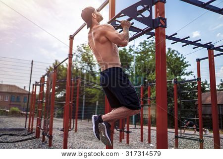 Brutal Athletic Man Making Pull-up Exercises On A Crossbar At Outdoor Streeet Gym.