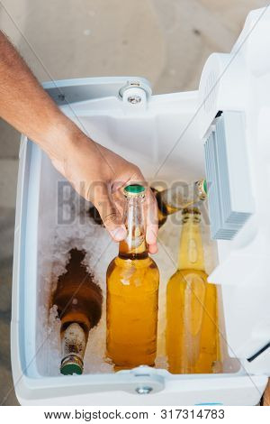 Cropped View Of Young Man Taking Bottle Of Beer From Portable Fridge