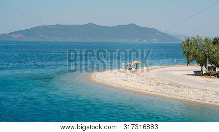 Empty Beach On A Greek Island With One Sunshade