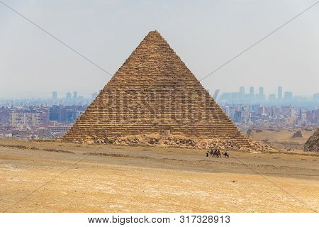 Camel Caravan With Tourists In Front Of The Great Pyramids Of Giza, Egypt
