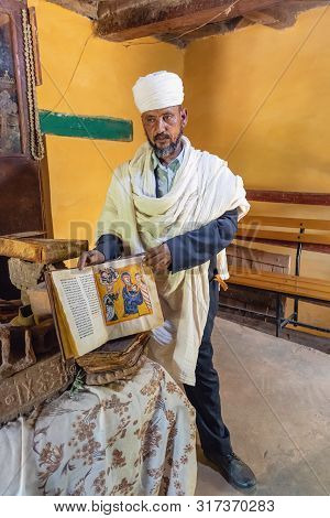 Yeha, Tigray Region, Ethiopia - April 28, 2019: An Orthodox Priest Shows A Painted Holy Bible From T