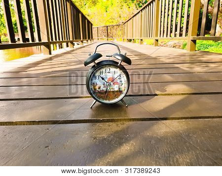 Old Alarm Clock On Wooden Table On Nature Background.