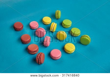 Colored Macaron Or Macaroon, Sweet Meringue-based Confection On Blue Background. Close-up, Copy Spac