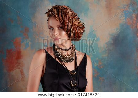 Southern Spices. A Beautiful Young Blue-eyed Woman With Afrocos And Large Ornaments Against A Textur