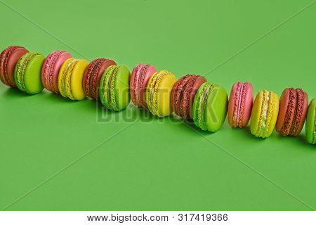 Colored Macaron Or Macaroon, Sweet Meringue-based Confection On Green Background. Close-up, Copy Spa