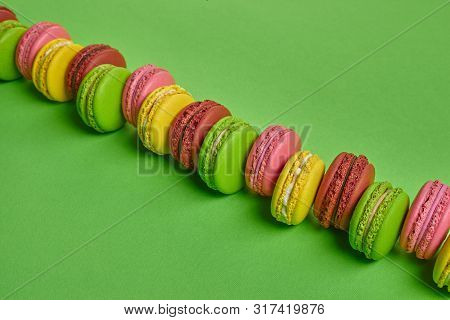 Colored Macaron Or Macaroon, Sweet Meringue-based Confection On Green Background. Close-up, Copy Spa