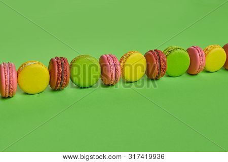 Colored Macaron Or Macaroon, Sweet Meringue-based Confection On Green Background. Close-up, Copy Spa
