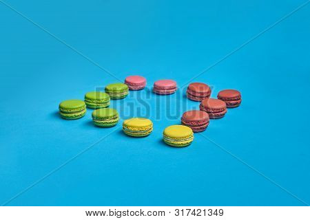 Colored Macaron Or Macaroon, Sweet Meringue-based Confection On Blue Background. Close-up, Copy Spac