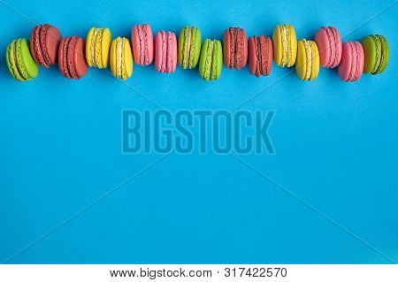 Colored Macaron Or Macaroon, Sweet Meringue-based Confection On Blue Background. Close-up, Copy Spac