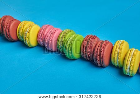 Colored Macaron Or Macaroon, Sweet Meringue-based Confection On Blue Background. Close-up, Copy Spac