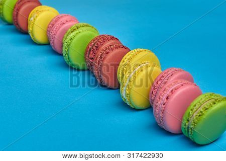 Colored Macaron Or Macaroon, Sweet Meringue-based Confection On Blue Background. Close-up, Copy Spac