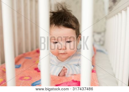 Baby In The Crib. Funny Baby In A White Canopy Bed. Childrens Room Interior And Bedding For Children