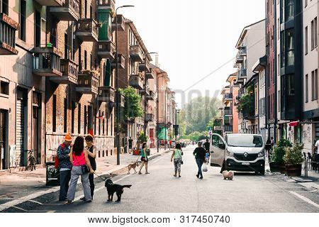 Milan, Italy - June 15, 2019: Italian Street In Summer. Local Residents And Tourists Walking Dogs On