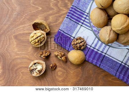 Whole Walnuts And Walnut Kernel Halves Without Shell On A Dark Wooden Table And Checkered Towel, Clo