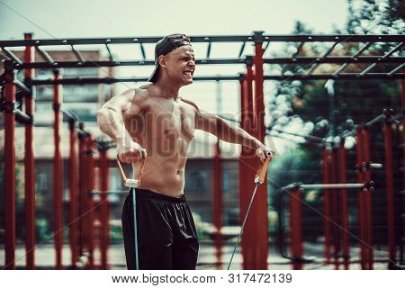 Fitness Man Exercising With Stretching Band. Muscular Sports Man Exercising With Elastic Rubber Band
