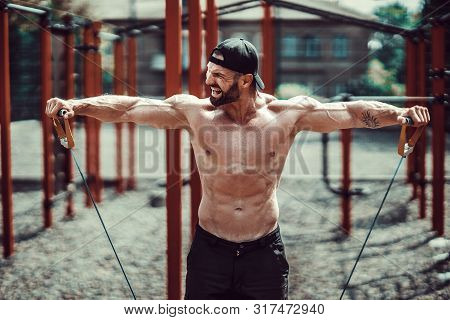 Fitness Man Exercising With Stretching Band. Muscular Sports Man Exercising With Elastic Rubber Band