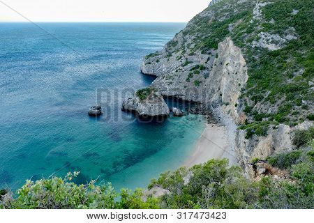 Secluded Beach With Blue Water And Mountains Surrounding It.
