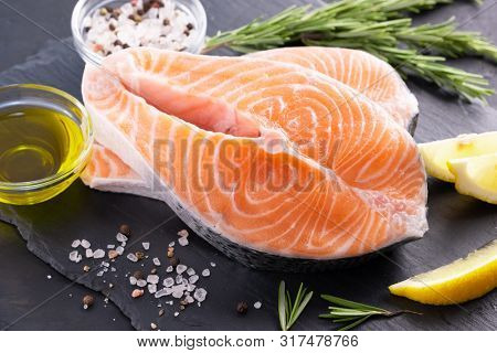 Raw, fresh salmon steak on a slate board and spices around. Raw salmon red fish. Cooking salmon, seafood. Healthy food concept. Salmon and spices
