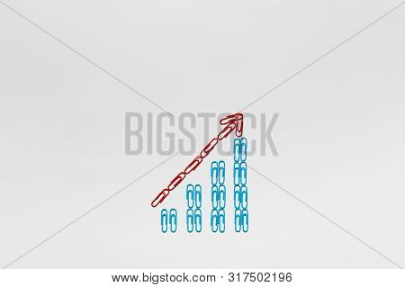 A Red Arrow Pointing Upwards Siting On A Stairwell Made From Blue Paperclips On White Background, Sh