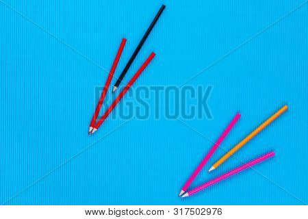 A Bunch Of Crayons Forming Arrows On An Blue Background, Shot From Above.