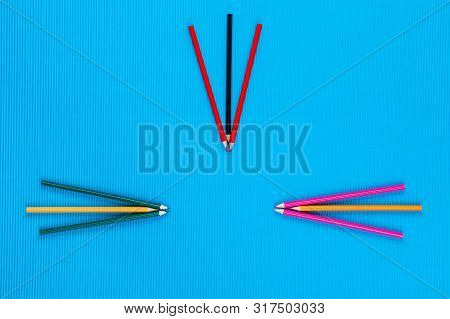 A Bunch Of Crayons Forming Arrows On An Blue Background, Shot From Above.