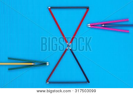 A Bunch Of Crayons Forming Arrows On An Blue Background, Shot From Above.