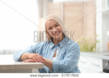 Portrait Of Happy Mature Woman At Table Indoors