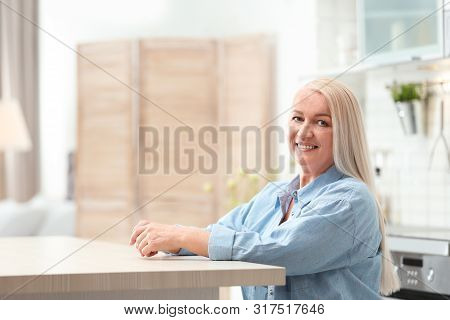 Portrait Of Happy Mature Woman At Table Indoors