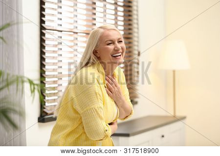 Portrait Of Happy Mature Woman Near Window Indoors