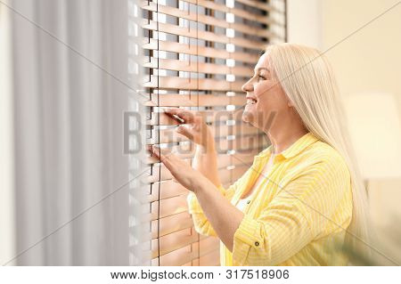 Portrait Of Happy Mature Woman Near Window Indoors