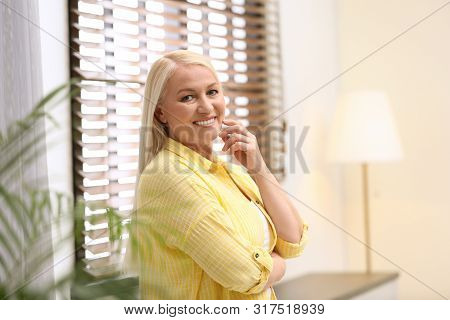 Portrait Of Happy Mature Woman Near Window Indoors