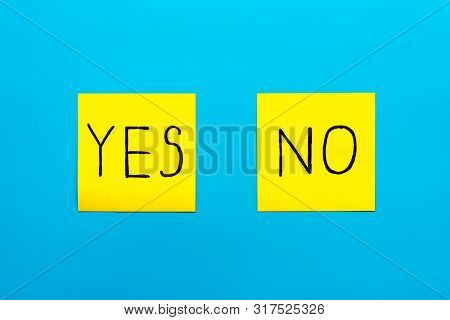 Close Up Black Handwritten Inscription Yes And No Word On Two Yellow Square Stickers On Blue Backgro