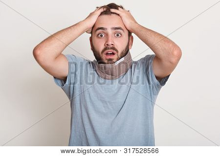 Close Upportrait Of Shocked Young European Man Keeping Hands On Head, Eyes Widely Open, Hears Terrib