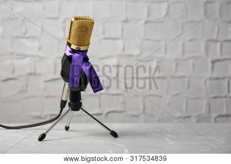 Microphone With Purple Awareness Ribbon On Table Against White Wall, Space For Text