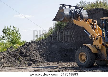 Wheeled Tractor With Bucket Clears The Soil Layer For Subsequent Construction