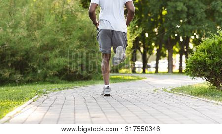 Fit Body Concept. Body Of Black Atlete Running Along The Park Path, Free Space