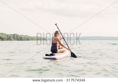 Middle Age Caucasian Woman Sitting Riding On Paddle Sup Surfboard At Sunset. Female Doing Individual