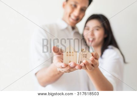 Happy Asian Couple In Love Showing Wooden House Model. Moving To New House Or Strating New Family Li