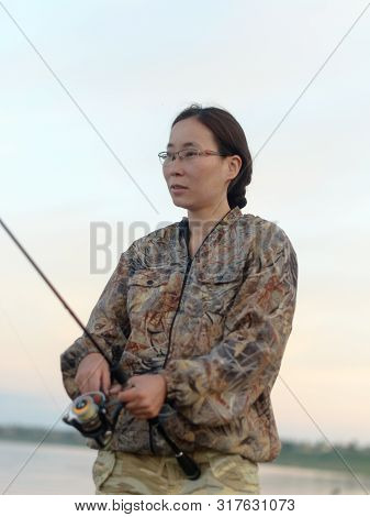 Yakut Girl-the Tourist-fisherman Carefully Turns The Handle Of The Fishing Reel To Catch Fish On The